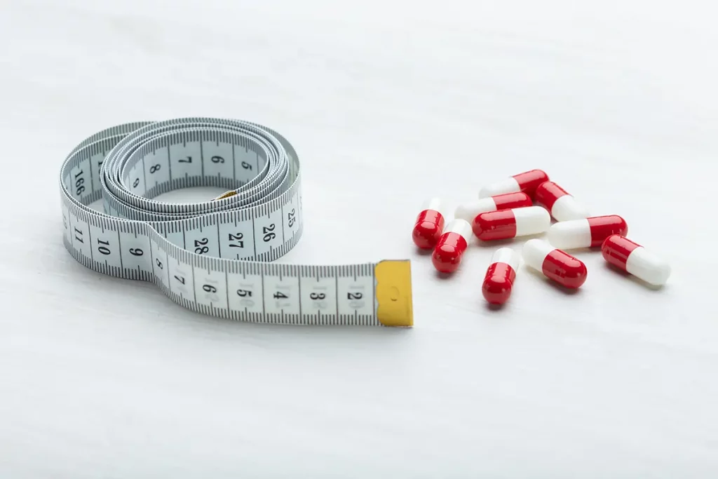 Cholin-Tabletten neben Maßband symbolisieren den Gewichtsverlust.
